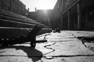 Black tactical gear including helmet and vest abandoned on concrete steps of empty university campus building