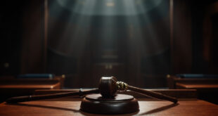 Wooden judge's gavel resting on polished mahogany surface in empty formal courtroom setting