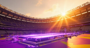 Empty football stadium with illuminated halftime show stage surrounded by dramatic lighting and staging equipment.