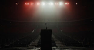 Empty stadium stage with lone microphone under bright spotlights, rows of vacant seats extending into darkness