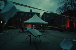 Empty white tent and overturned table on university campus with scattered papers and police tape