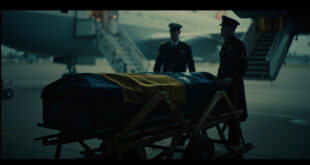 Flag-draped mahogany coffin beside government aircraft on airport tarmac under dramatic lighting