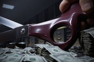 Large scissors cutting through thick bundles of dollar bills on a government desk with budget documents scattered around