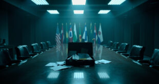 Open diplomatic briefcase with documents scattered on conference table under harsh lighting