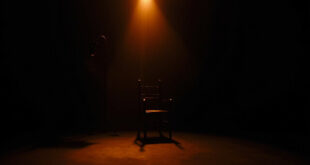 Empty black chair at podcast recording desk under focused studio lighting in darkened room