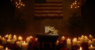 Memorial podium with flowers, candles, and photographs in solemn lighting setup