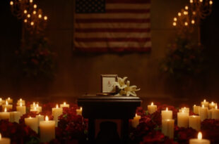 Memorial podium with flowers, candles, and photographs in solemn lighting setup