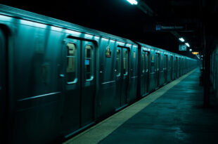 Empty subway train at dark station platform, closed doors, overhead lights casting long shadows on concrete