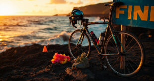 Triathlon gear and bicycle at Hawaiian coastal finish line with ocean and volcanic rock landscape at sunset