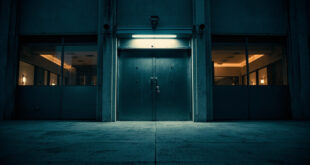 Heavy steel security door of broadcasting facility with mounted surveillance camera against concrete wall