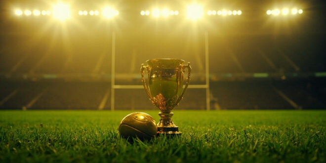 Championship rugby trophy stands illuminated on empty grass field under stadium floodlights