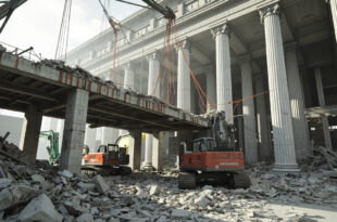 Demolished East Wing with exposed framework, construction cranes, and debris from historic white building exterior.