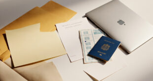 Closed passport with visa stamps rests on desk beside university admission letters and official immigration documents