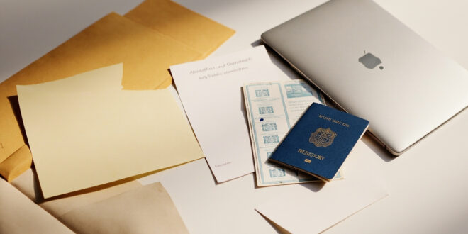 Closed passport with visa stamps rests on desk beside university admission letters and official immigration documents