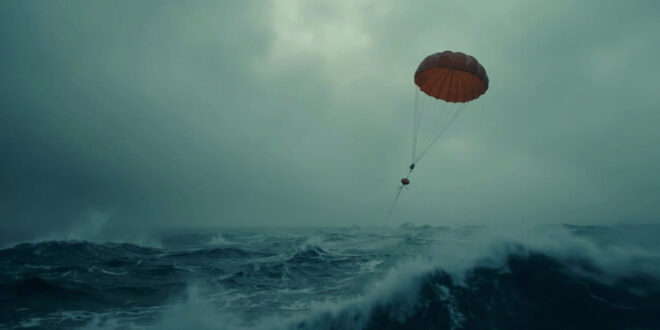 Orange sonar buoy with parachute falling toward dark Atlantic ocean surface from aircraft