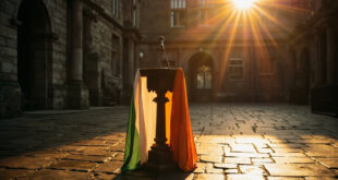 Empty wooden podium with microphone and Irish tricolor flag in historic Dublin Castle courtyard at twilight