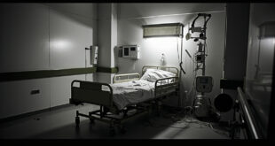 Empty hospital bed with IV stand and medical equipment in bare clinical ward