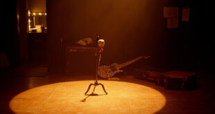 Empty wooden stage with vintage microphone stand under warm spotlight, guitar case and amplifier visible in shadows