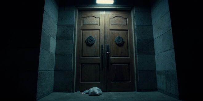 Heavy government door with electronic lock and evidence bag in harsh lighting, concrete walls frame the entrance