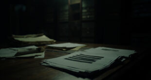 Stack of heavily redacted legal documents with black censorship bars on dark wooden surface