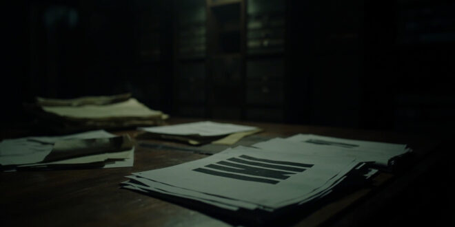 Stack of heavily redacted legal documents with black censorship bars on dark wooden surface