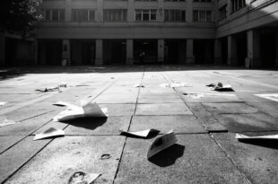 Chalk markings and scattered flyers on concrete pavement in front of administrative building entrance