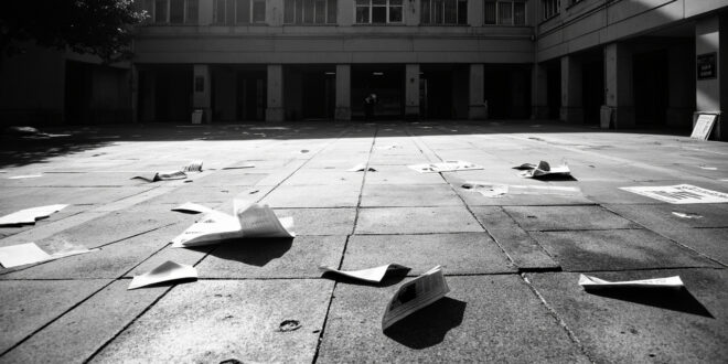 Chalk markings and scattered flyers on concrete pavement in front of administrative building entrance