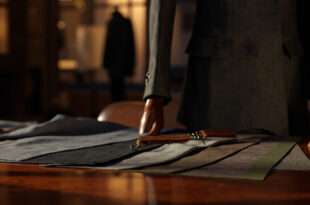 Leather crafting tools and fabric samples on wooden workbench in luxury fashion studio