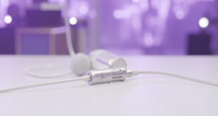 Medical port device positioned next to vintage microphone on clean white surface with purple stage lighting in background