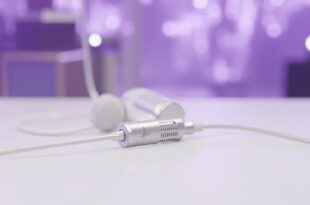 Medical port device positioned next to vintage microphone on clean white surface with purple stage lighting in background