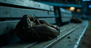 Solitary baseball glove on wooden dugout bench with soft stadium lighting in background
