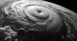 Satellite image showing massive spiral hurricane system with defined eye wall over dark ocean waters
