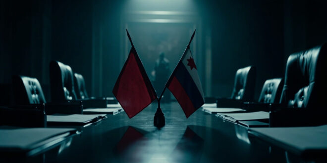 Two national flags crossed on polished wooden conference table in austere government office setting
