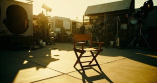 Empty director's chair on outdoor film set with camera equipment and lighting rigs under California sun