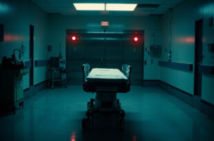 Hospital gurney in empty corridor facing closed operating room doors with overhead surgical lights