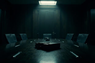 Empty government conference room with abandoned briefcase on dark wooden table under dramatic overhead lighting