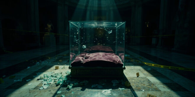 Shattered glass display case with empty velvet cushion in ornate museum gallery under dramatic lighting