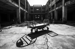 Overturned hospital gurney on cracked concrete with damaged building facade and debris in harsh sunlight