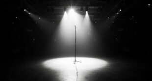 Single microphone stand illuminated by spotlight on empty stadium stage with rows of vacant seats in darkness