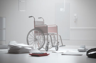 Empty wheelchair next to scattered budget documents and calculator on government desk