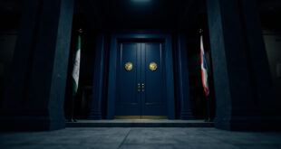 Closed ornate doors in government building hallway with flags and official architectural details