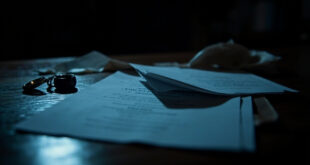Divorce papers scattered on dark wooden desk with wedding rings and legal stamps in dramatic lighting