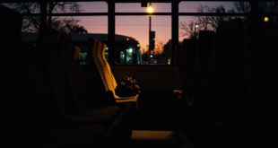 Empty bus seat with small backpack in dim evening light inside parked public transit vehicle