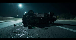 Overturned damaged SUV wreckage on empty highway at night with scattered debris and emergency lighting