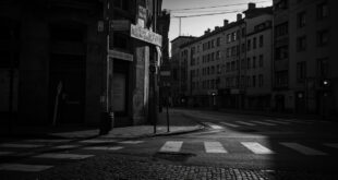 Empty Berlin street corner with weathered signpost and residential buildings under overcast evening sky