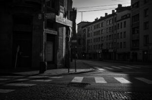 Empty Berlin street corner with weathered signpost and residential buildings under overcast evening sky