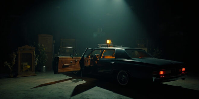 Open car door on dark soundstage with dramatic lighting and scattered memorial flowers nearby
