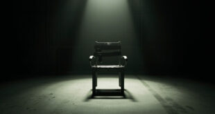 Empty metal restraint chair with leather straps in stark institutional room with concrete walls