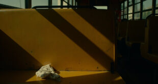 Empty yellow school bus interior with a crumpled piece of paper on a seat, dramatic lighting and emergency colors