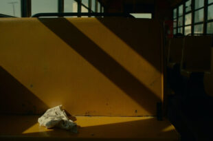 Empty yellow school bus interior with a crumpled piece of paper on a seat, dramatic lighting and emergency colors
